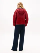 Campera puffer ligera roja con capucha y cierre frontal de cremallera. Presenta diseño acolchado horizontal, bolsillos laterales con cierre y el logo bordado en el pecho.