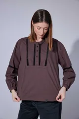 Camisa blanca de algodón con pechera decorada con alforzas y puntillas. Presenta cierre frontal con botones, mangas tres cuartos con frunces y detalles de puntilla, y un diseño de corte holgado con ruedo redondeado.