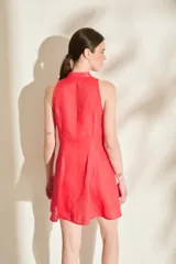Vestido corto de lino color rojo, sin mangas, con cuello mao y cierre frontal de botones. Presenta falda con vuelo gracias a sus godettes.