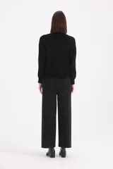 Sweater de punto color beige con cuello alto tipo polera, manga larga y detalle de botones decorativos en el hombro y cuello.