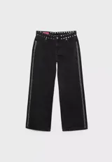 Jean de corte recto y tiro bajo, color negro, con detalle de tachas metálicas en la cintura y una banda lateral de brillos a lo largo de la pierna.