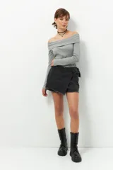 Short pollera de jean prelavado color negro, con lazo en uno de sus laterales y detalle de flecos en las terminaciones.