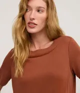 Vestido corto marrón oscuro, estilo camiseta, con escote redondo, mangas cortas y bolsillos laterales. El bajo es redondeado.