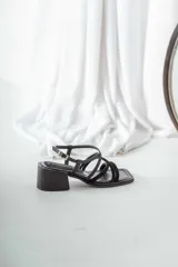 Sandalias de cuero negro con tiras finas cruzadas, taco cuadrado y hebilla lateral.