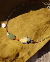 Collar corto de cuentas de colores con dije de pez de cerámica, piedras naturales y detalles en plata 925.