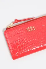 Billetera compacta Bimba y Lola de estructura rígida con textura efecto cocodrilo y acabado brillante. Cuenta con cierre de cremallera superior con tirador de tela, logo metálico dorado en el frente y compartimentos internos para tarjetas y monedas.
