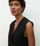 Chaleco alargado de Marfinno, confeccionado en tejido de punto con estructura encorpada. Presenta un diseño recto con cierre delantero cruzado de cuatro botones, dos bolsillos aplicados en el frente y sisa amplia.