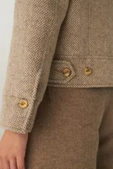 Campera de lana fina sin teñir, con cuello alto, cierre frontal completo y diseño de corte recto con pespuntes decorativos en puños, ruedo y cuello.