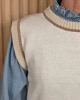 Chaleco tejido de punto color verde con detalles en tostado en el cuello redondo, sisas y dobladillo inferior.