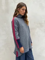 Sweater de punto con patrón de espiga en tonos beige y marrón, cuello alto, mangas largas con detalles en naranja y puños marrones.