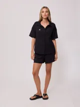 Short negro de algodón y lino con cintura elástica ajustable con cordón y parche bordado en la pierna derecha.