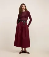 Pollera evasé midi color borgoña, confeccionada en tricolina de algodón sostenible, con tiro alto, pliegues delanteros y cierre trasero por cremallera.