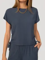 Conjunto de dos piezas compuesto por una remera de manga corta con cuello redondo y frunces laterales ajustables, y un pantalón de corte ancho con cintura elástica y bolsillos laterales.