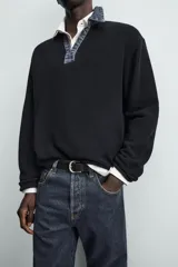 Polo de punto color azul marino, de calce relajado y manga larga. Presenta un cuello solapa de tejido denim en contraste con una abertura frontal en forma de V.