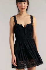 Mini vestido slip negro de tela liviana y fruncida, con escote corazón, cierre delantero regulable de gancho, tiras regulables y encaje translúcido en los bordes y el ruedo. Silueta entallada en la parte superior y con vuelo en la falda.