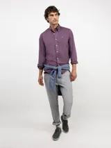 Camisa de hombre color azul, con cuello buttondown, cierre frontal con botones y logo bordado en el pecho. Presenta un acabado vintage logrado mediante el proceso de teñido en prenda.