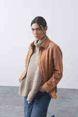 Sobrecamisa de gamuza color tostado con diseño estilo western, presenta bordados decorativos en la zona de los hombros y cierre frontal con botones a presión.