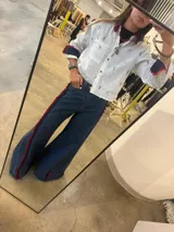 Jean de corte wide leg en denim azul oscuro, con detalle de franja lateral decorativa en color rojo y ruedo deshilachado.