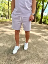 Conjunto deportivo compuesto por una remera de manga corta y un short lila con cordón de ajuste blanco.