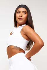 Top deportivo negro, estilo crop top, con cuello polo y escote en V. Presenta tirantes anchos y corte ajustado al cuerpo.