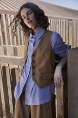 Chaleco sastrero color marrón, con escote en V, cierre frontal de botones y pinzas de entalle.