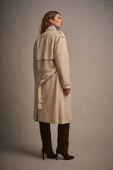 Trench de gamuza color beige, con solapas amplias, charreteras en los puños y cinturón de la misma tela.