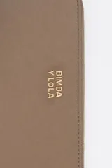 Billetera mediana de estructura rígida en color marrón topo, con cierre perimetral de cremallera y tirador decorativo de cordón. Presenta el logo de la marca aplicado en letras metálicas doradas en el frente.