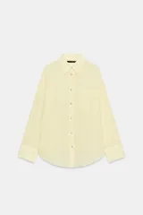 Camisa de corte oversize confeccionada en tejido de gasa color amarillo claro. Presenta cuello solapa, cierre frontal con botones, manga larga con hombro caído y puños definidos, además de un bolsillo de plastrón en el frente y detalle de pinza en la espalda.