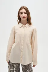 Camisa de algodón con estampado de rayas verticales finas, cuello camisero, cierre frontal con botones y bolsillos frontales tipo parche.