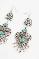 Aro colgante de estilo étnico con diseño de corazón calado, adornado con piedras turquesas y pequeños dijes colgantes en la parte inferior.