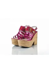 Sandalias de plataforma corrida revestida en corcho, con tiras delanteras de cuero fucsia brillante y tira ancha superior con detalles textiles multicolor estilo aguayo. Presenta cierre con hebilla en el talón.