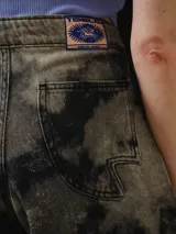 Short de tiro alto confeccionado en denim con lavado Overo de efecto irregular en negro y gris. Presenta una silueta corta y levemente evasé con pierna amplia, ruedo curvo y recortes delanteros Rayo definidos mediante pespuntes visibles, además de pretina estructurada con cierre frontal y botón metálico.