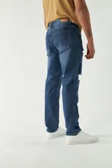 Pantalón de jean azul oscuro con roturas en las rodillas, corte recto y logo bordado en el bolsillo trasero.