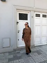 Conjunto de dos piezas compuesto por una remera de manga corta y un pantalón de corte acampanado, ambos confeccionados en lanilla con estampado animal print en tonos marrones.