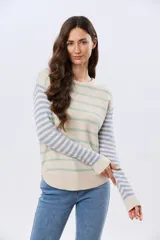 Buzo tejido de algodón con diseño a rayas horizontales, cuello redondo y mangas largas. El cuerpo presenta rayas en tonos azul y beige, mientras que las mangas combinan rayas en tonos azul y rosado.
