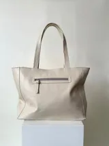 Cartera tipo shopper de cuero marrón texturado, con doble asa de hombro y un bolsillo frontal amplio con cierre de imán.