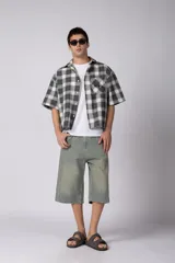 Camisa de manga corta de popelina cuadrillé en tonos marrón, blanco y gris, con diseño boxy fit, cuello camisero, cierre frontal de botones, bolsillo en el pecho con detalle bordado y dobladillo recto.