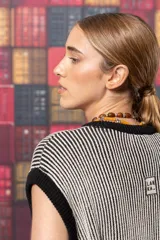 Chaleco largo de punto con rayas verticales en tonos beige y negro. Tiene cuello redondo, sisas amplias con ribete negro y aberturas laterales en el ruedo.