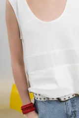 Musculosa blanca de algodón orgánico con escote en U, cortes irregulares y mezcla de texturas. Tiene un fit holgado y cinta aplicada en la espalda con bordado frutal.