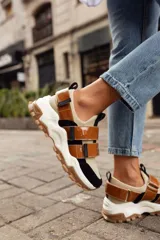 Championes de estilo urbano en color blanco con detalles en tono arena. Presentan un diseño con doble tira de velcro en el empeine, suela de plataforma dentada en color caramelo y tirador en el talón.
