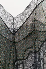 Top estampado con diseño geométrico en tonos verdes y marrones, confeccionado en viscosa 100%. Presenta escote en pico, tirantes finos y detalle de encaje negro a contraste. El bajo tiene un acabado asimétrico.