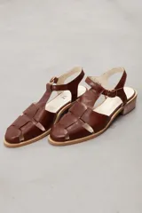 Sandalias tipo guillermina y estilo pescador de cuero marrón, con diseño de tiras entrelazadas, taco bajo cuadrado y tira con hebilla ajustable al tobillo.