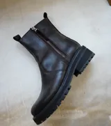Botas de cuero marrón con suela track de goma negra, cierre lateral en color rojo y detalle de tira trasera al tono.