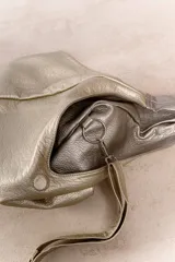 Bolso de hombro color beige, confeccionado en cuero sintético con interior plateado. Presenta un bolsillo externo con cierre.