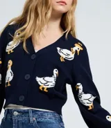 Cardigan cropped de punto jacquard color azul marino con diseño de patos estampados. Presenta escote en V, cierre frontal con botones y mangas largas con puños acanalados.
