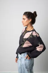 Buzo de punto color negro con estampado floral en tonos rosado y verde. Presenta cuello redondo, mangas largas con diseño abullonado y corte holgado.