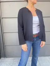 Cardigan negro de tejido fino en lana, con cuello redondo, cierre frontal con botones y detalle de cuero en los puños.