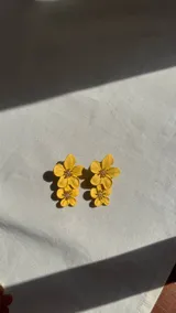 Par de aros colgantes con forma de flores amarillas.