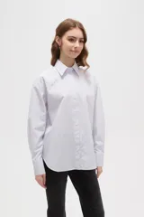 Camisa de algodón a rayas verticales, con cuello camisero, cierre frontal de botones y detalle de strass aplicado en la parte superior delantera.