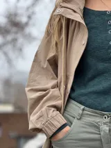 Campera de estilo casual color beige, con cierre frontal, botones a presión y puños elásticos.